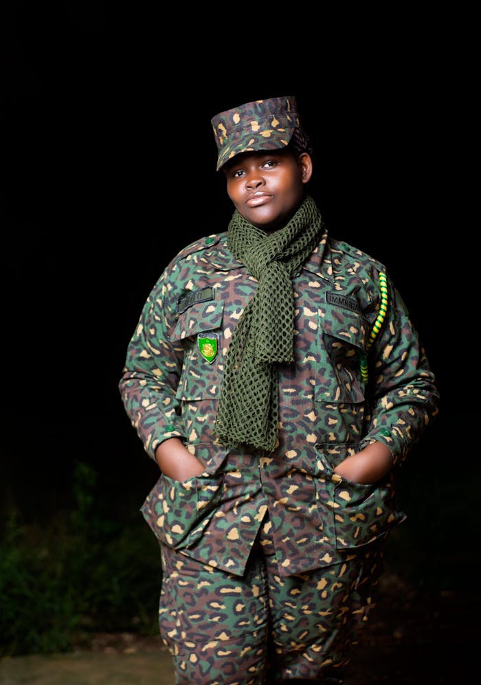Confident soldier posing in full camouflage gear at night.